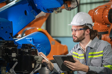 male automation engineer in uniform helmet safety inspection check control heavy machine robot arm system in industrial factory. technician worker check for repair factory machine