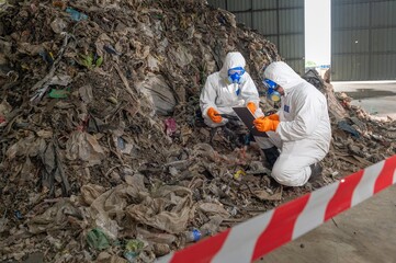 Environmental Cleanup Team in Full Protective Gear Removing Hazardous Waste from Landfill Site for...