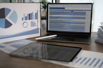 Report file modern workspace with laptop displaying spreadsheet, tablet showing data, and...