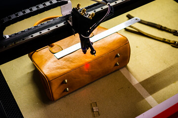The process of making laser engraving on brown leather bags, perfect for leather industry company profile designs