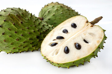 Whole and sliced soursop (guyabano) tropical fruit on white background