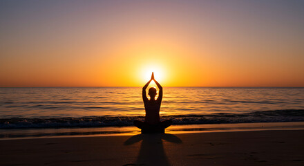 Fototapeta premium Silhouette of a woman in lotus position with hands raised at sunset