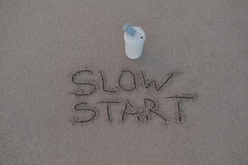 Slow Start – Handwritten Message on Volcanic Sand with Thermos Mug