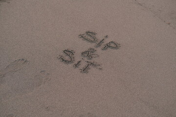 Sip and Sit – Handwritten Message on Volcanic Sand
