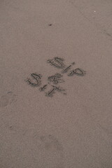 Sip and Sit – Handwritten Message on Volcanic Sand