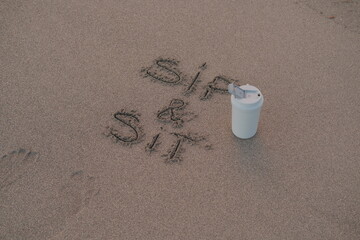 Sip and Sit – Handwritten Message on Volcanic Sand with Thermos Mug