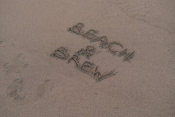 Beach and Brew – Handwritten Message on Volcanic Sand
