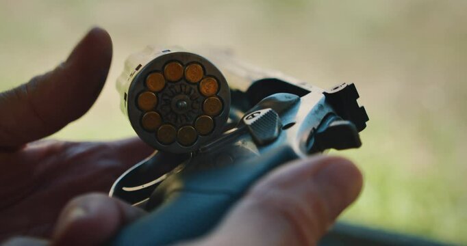 Closeup view of loaded revolver cylinder held in hands at shooting range outdoors