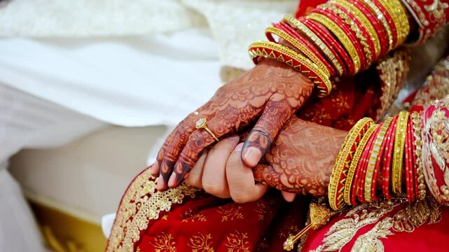 Wedding couple hold by the hands of each other, dressed in traditional red Indian clothes, Elements of hindu wedding. Close up