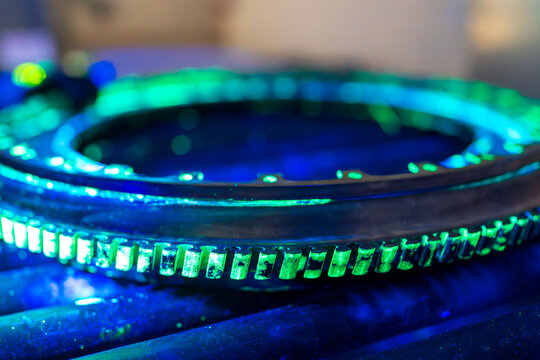 A high-precision aerospace component is undergoing fluorescent penetrant testing with distinctive green indications. Non-destructive evaluation exposes  discontinuities in this critical flight safety 