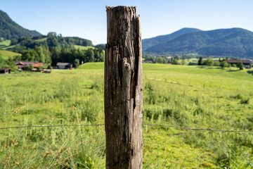Old wooden fence post in countryside with mountains in the background