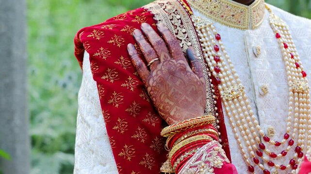 Bride put an arm on the groom , dressed in traditional red and white Indian clothes, Elements of hindu wedding. Close up