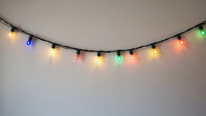 Colorful string of Christmas lights hanging from a wall. The lights are bright and colorful, creating a festive and cheerful mood