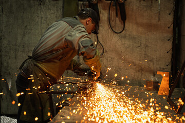 Industrial Metalworker Using Angle Grinder in Workshop with Flying Sparks