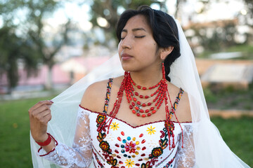 Latin bride wearing traditional dress and veil, holding it gently
