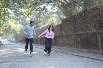 Fototapeta premium A joyful young couple sharing a loving moment on a peaceful street surrounded by greenery