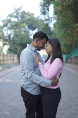 A joyful young couple sharing a loving moment on a peaceful street surrounded by greenery