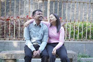 A joyful young couple sharing a loving moment on a peaceful street surrounded by greenery