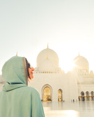Abu Dhabi, UAE - april 25th, 2025: woman traveler portrait wear stylish abaya sightseeing Sheikh Zayed Grand Mosque in Abu Dhabi on beautiful sunset. UAE famous travel destination concept