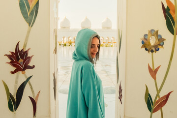 Traveling by United Arabic Emirates. Woman in traditional abaya standing in the Sheikh Zayed Grand Mosque, famous Abu Dhabi sightseeing.