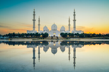 Illuminated Sheikh Zayed Grand Mosque with reflections at sunset, Abu Dhabi, UAE. Tourist sightseeing famous grand mosque attraction in United arab emirates. 4k high quality colorful day to night