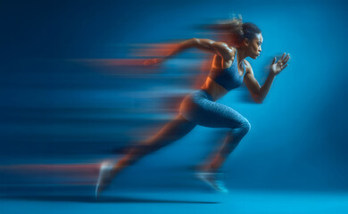 Motion blurred photo of female runner running in action pose with fast pace on bright blue gradient background. Commercial sports photography style.
