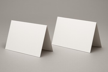 Naklejka premium Blank Place Cards: A minimalist pair of blank place cards stand side-by-side, their pristine surfaces and clean lines offer versatility for customized messaging, waiting to be filled with invitations.