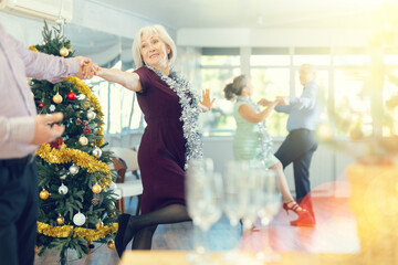 Middle-aged man and elderly woman are dancing contemporary discofox in couple during lesson at studio in New Year atmosphere. Leisure activities and hobby for positive people.