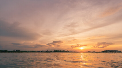 Sunset sky clouds over sea water background in evening with orange, blue sun light, Horizon sea ocean sunrise sky landscape nature backgrounds and gold sun down in golden hour summer season, Dusk sky