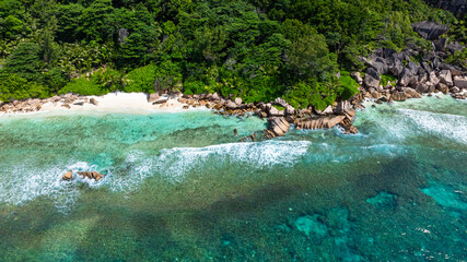 Aerial view of Idyllic beach with bright blue water and dense greenery. La Digue, Seychelles. Anse Caiman.