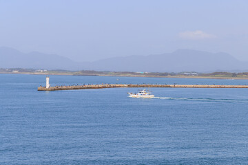 防波堤の上で海釣りを楽しむ人々と釣り船