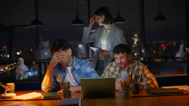 Annoyed startupers looking computer screen worried problem at overtime office