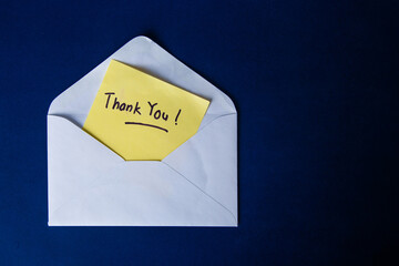 White envelope containing thank you note on blue background