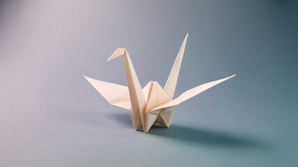 Beige paper origami crane placed on a flat surface with shadow