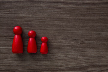 Red family figures standing on dark wood background symbolizing family values