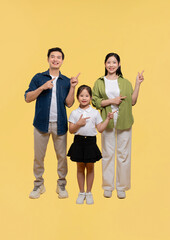 Fototapeta premium Family of three points to the side against a yellow background Smiling and looking forward