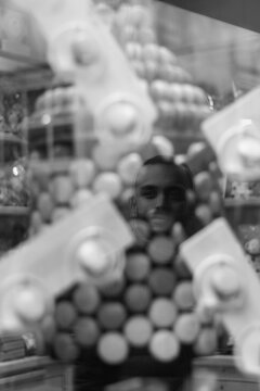 Retrato del reflejo de un chico joven que pasea por Par&iacute;s y se refleja en un escaparate de macarrons