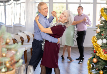 Positive senior man dancing playful Latin dance bachata with female partner during celebration...