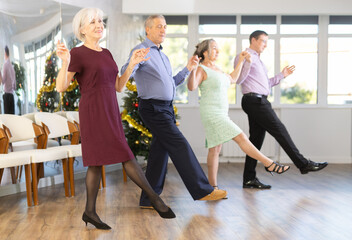 Group men and women dancing folk dance in row in studio..