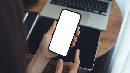 Mockup, Woman using mobile phone with blank white screen while online working on laptop at coffee shop. Business woman using smartphone, mockup for online marketing, mobile app, closeup