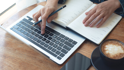 Event planner timetable agenda plan on work schedule. Business woman, event manager checking, working on laptop computer, taking note on calendar planner notebook on table. work organizing