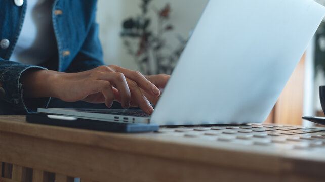 Woman working on laptop computer on table in coffee shop, freelance at work. Woman online working, typing on laptop computer, surfing the internet at cafe, remote work, online job, close up
