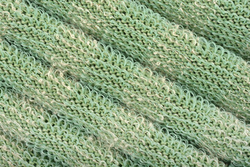 A macro detail of green knitted fabric with a unique texture and protruding plastic threads