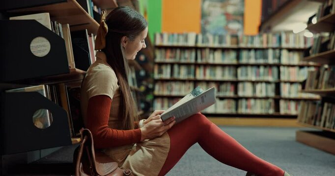 Happy woman, student or laughing with book in library for comedy, funny joke or humor. Female person, learner or reading with smile or novel on floor in joy for comic, genre or amusement by bookshelf