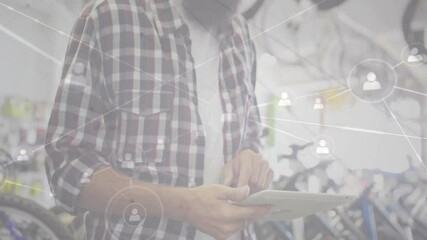shop employee glancing at tablet in shop, tapping and growing network overlay on wheels and frames