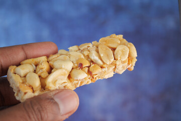 Nut snack bar held in hand against a blue background