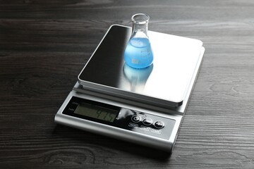 Laboratory scale with flask of sample on wooden table, closeup
