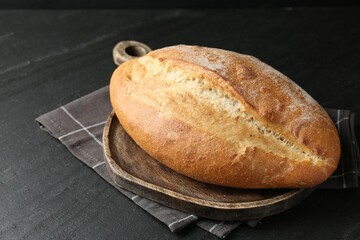 Loaf of bread on black textured table, closeup