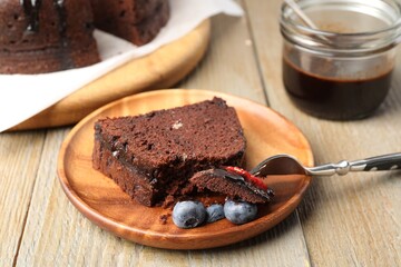 Piece of delicious chocolate bundt cake with blueberries on wooden table, closeup