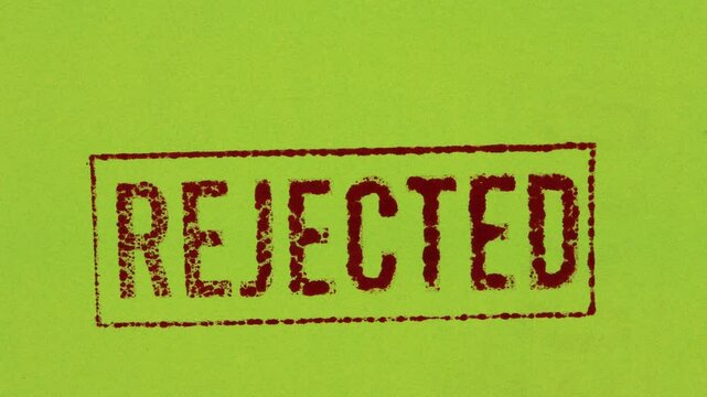 Close-up of a red REJECTED stamp sign on a green background